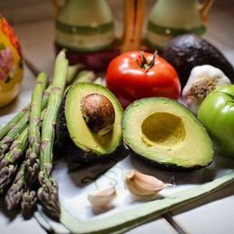 sparagus, avocado, tomato, garlic on a plate